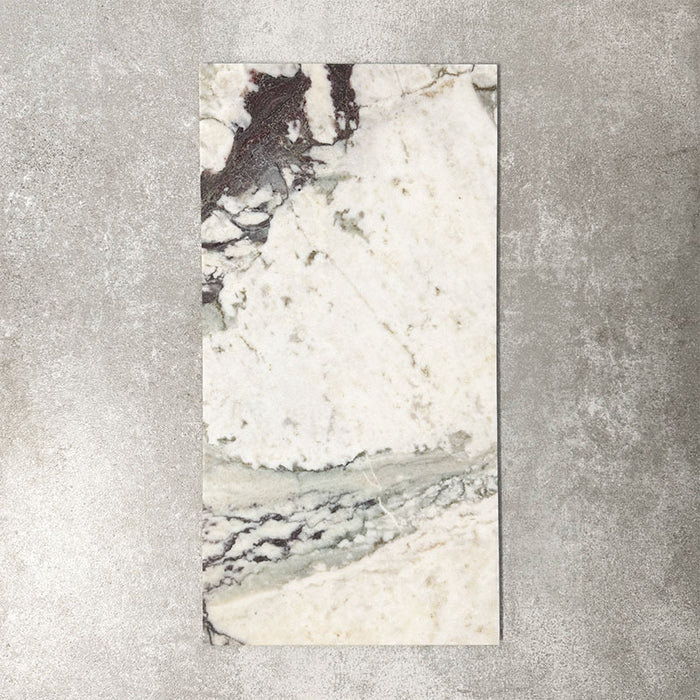 Fayrouz Viola 30.5x61cm natural marble tiles with a honed finish, featuring a warm ivory base with bold burgundy and green veining, shown as a single tile sample against a neutral textured backdrop.