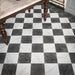 Vitoria Antique Black 30cm x 30cm marble effect chequerboard tiles, featuring a deep charcoal finish paired with white marble effect tiles to create a classic checkerboard floor, framed with a coordinating dark border.