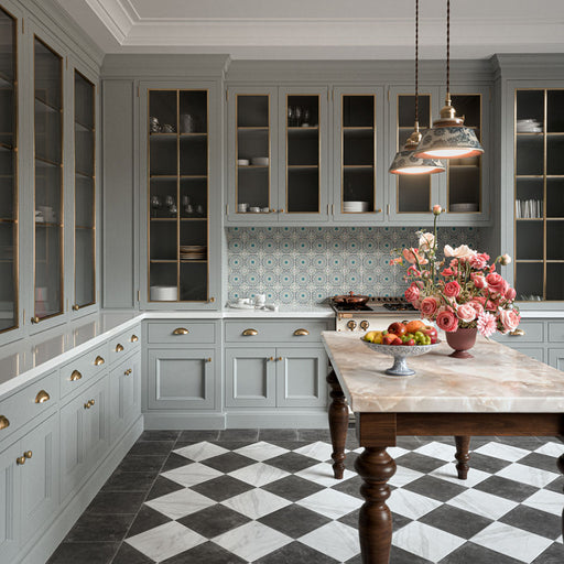 Vitoria Antique White 30cm x 30cm marble effect chequerboard tiles, creating a classic black and white kitchen floor, paired with soft grey cabinetry, brass details and a statement marble island.