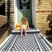 Front garden walkway featuring Fulham Tile Black & White Victorian-style porcelain wall and floor tiles in a 25 × 25cm format, laid in a bold geometric pattern with a contrasting border, creating a striking entrance to a period brick home with a painted front door.