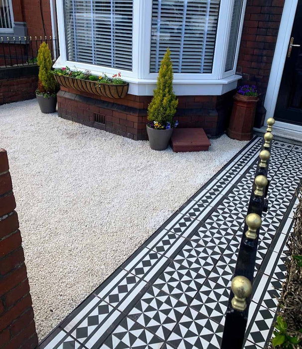 Front garden walkway featuring Fulham Tile Black & White Victorian-style porcelain wall and floor tiles in a 25 × 25cm format, laid in a classic geometric pattern with a framed border, creating a striking path to a traditional brick house with wrought iron gates.