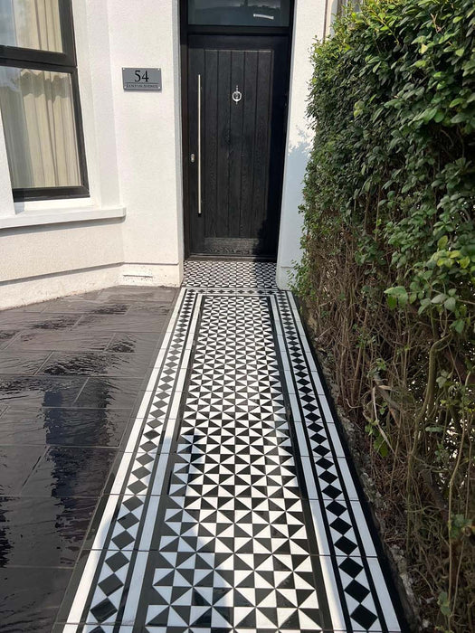 Front garden walkway featuring Fulham Tile Black & White Victorian-style porcelain wall and floor tiles in a 25 × 25cm format, laid in a classic geometric pattern with a decorative border, creating a smart and timeless path leading to a modern black front door.