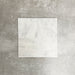 Four Fayrouz White 15.2x15.2cm natural marble tiles with a tumbled finish arranged together, showcasing soft white tones, subtle veining and natural variation against a neutral textured background.