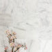 Flat lay of Fayrouz White 15.2x15.2cm natural marble tiles with a tumbled finish, featuring soft white tones and subtle natural veining, styled with delicate pink blossom branches for a calm, elegant look.