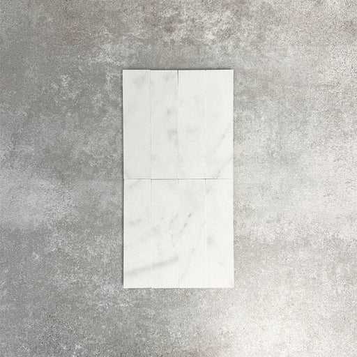 Fayrouz White 5x20cm natural marble tiles with a honed finish, featuring a soft white base with subtle grey veining, arranged in a neat grid to highlight natural variation and tonal consistency.