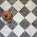 Chequerboard layout featuring Fayrouz White 15.2x15.2cm natural marble tiles with a tumbled finish, paired with black marble tiles, installed diagonally and styled with a decorative patterned dish for added visual contrast.