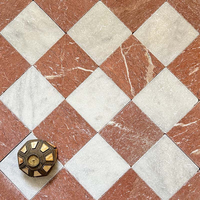 Chequerboard layout featuring Fayrouz White 15.2x15.2cm natural marble tiles with a tumbled finish, paired with Rosso marble tiles, installed diagonally and styled with a decorative object for added warmth and contrast.