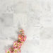 Flat lay of Fayrouz White 15.2x15.2cm natural marble tiles with a honed finish, featuring soft white tones and subtle natural markings, styled with delicate pink blossom branches for a calm, elegant look.