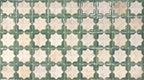 Close-up of Zanzibar Moroccan Emerald Green ceramic wall tiles featuring a repeating Moroccan style geometric star pattern in soft emerald green and warm ivory tones, with a glossy glazed finish and subtle distressed detailing for an authentic handcrafted look.