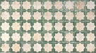 Close-up of Zanzibar Moroccan Emerald Green ceramic wall tiles featuring a repeating Moroccan style geometric star pattern in soft emerald green and warm ivory tones, with a glossy glazed finish and subtle distressed detailing for an authentic handcrafted look.