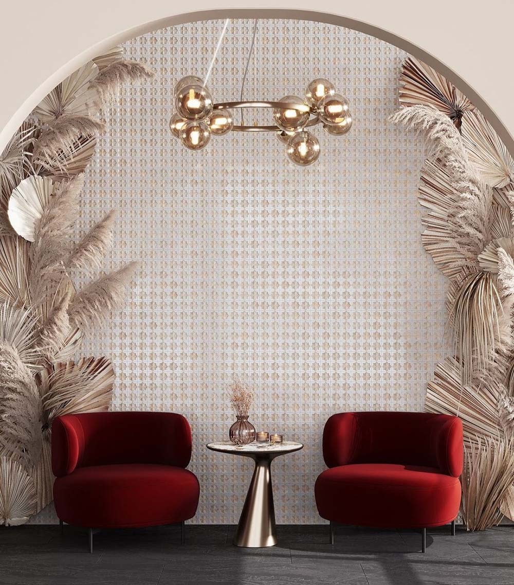 Feature wall featuring Zanzibar Moroccan Natural White ceramic wall tiles in a repeating Moroccan style geometric pattern, framed by an elegant arched alcove with decorative dried palm leaves, plush burgundy lounge chairs, brass lighting and dark floor tiles for a luxurious boutique-inspired interior.