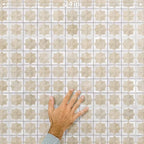 Close-up of Zanzibar Moroccan Natural White ceramic wall tiles in a repeating Moroccan style geometric star pattern, shown with a hand for scale to highlight the 31 x 56cm format, glossy glazed finish and subtle tonal variation.