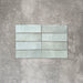 Flat lay of Zellige Aqua 6.5×20cm Moroccan-style ceramic brick tiles, showcasing soft blue-green tones, a glossy handmade-look glaze and subtle tonal variation on a neutral background.