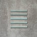Flat lay of Zellige Aqua 3×20cm Moroccan-style ceramic bullnose tiles, showcasing the rounded edge profile, glossy blue-green glaze and subtle tonal variation on a neutral background.