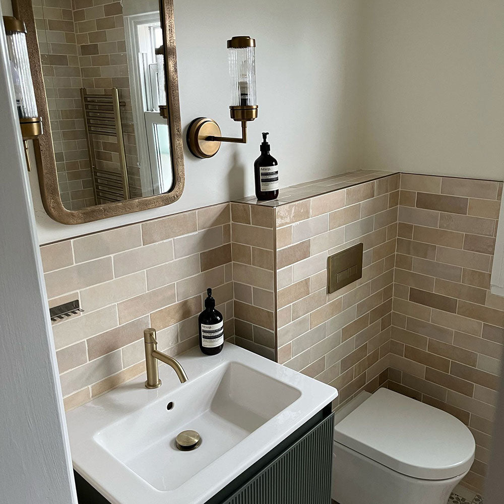 Bathroom featuring Zellige Bone Moroccan-style brick tiles in warm neutral tones, paired with brass fixtures and a compact vanity.