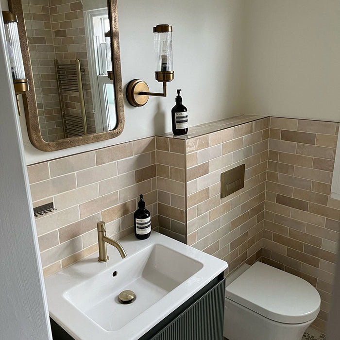Bathroom featuring Zellige Bone Moroccan-style brick tiles in warm neutral tones, paired with brass fixtures and a compact vanity.