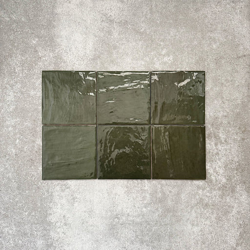 Flat lay showcasing Zellige Botanical Green Square 13.2 × 13.2cm Moroccan-style ceramic tiles, featuring rich botanical green tones, a glossy handcrafted zellige-effect glaze and natural tonal variation, arranged on a neutral textured background to highlight their artisanal character.