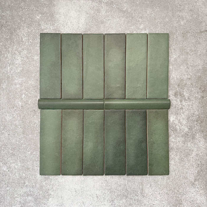 Flat lay of Zellige Malachite Green Moroccan-style ceramic tiles, showing 6.5×20cm brick tiles paired with a 3×20cm bullnose trim, highlighting the rounded edge detail, handmade-look texture and natural green tonal variation.