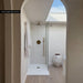 Bathroom interior featuring Zellige Oyster Brick 6.5x20cm Moroccan style tiles in soft neutral tones, installed vertically in a walk-in shower, styled with brass shower fittings, glass screen and natural textures in a calm contemporary space.