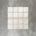 Zellige Oyster square tiles with matching bullnose trim in an oyster white finish, laid flat to show texture and shape.