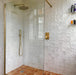 Walk-in shower featuring Zellige Oyster Square Moroccan-style ceramic tiles in a 10 × 10cm format, laid in a uniform grid across the walls, with a glossy oyster-white glaze, gently uneven surfaces and subtle tonal variation, paired with brushed brass shower fittings and a glass screen for a warm, handcrafted bathroom finish.