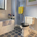 Bathroom featuring Zellige Oyster Square Moroccan-style ceramic tiles in a 10 × 10cm format, installed in a neat grid around the bathtub, with a glossy oyster-white glaze, softly uneven surfaces and subtle tonal variation creating a handcrafted backdrop that contrasts beautifully with the patterned floor tiles and classic bathroom fittings.