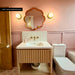 Bathroom featuring Zellige Oyster Square 10cm x 10cm Moroccan style wall tiles around the basin, paired with soft pink panelling, patterned floor tiles, brass details and a scalloped mirror.