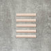Flat lay of Zellige Pink Mist Bullnose 3 × 20cm Moroccan-style ceramic trim tiles in soft pale pink tones, displayed with a smooth rounded edge and glossy glaze, arranged on a textured grey background to highlight the handcrafted zellige-effect finish and decorative edging profile.