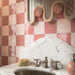 Close-up of Zellige Pink Mist Square 13.2x13.2cm Moroccan-style bathroom wall tiles, featuring glossy blush pink tones in a chequerboard pattern alongside rose pink tiles, a marble-effect washbasin and chrome taps.