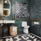 Bathroom featuring Zellige Royal Green Brick 6.5 × 20cm Moroccan-style ceramic wall tiles in rich deep green tones, laid in a horizontal brick layout throughout the space, paired with brass fittings, a wall-mounted basin and graphic floor tiles for a bold, characterful zellige-effect finish.