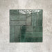 Flat lay of Zellige Royal Green Brick 6.5 × 20cm Moroccan-style ceramic tiles in rich deep green tones, arranged in a basketweave layout on a textured grey background, showcasing the glossy glaze, natural tonal variation and handcrafted zellige-effect finish.