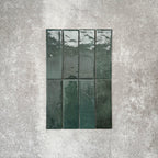 Flat lay of Zellige Royal Green Brick 6.5 × 20cm Moroccan-style ceramic tiles in rich deep green tones, arranged in a vertical brick layout on a textured grey background, showcasing the glossy glaze, natural tonal variation and handcrafted zellige-effect finish.