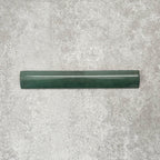 Zellige Royal Green Bullnose 3 × 20cm Moroccan-style ceramic trim tile in rich deep green tones, displayed with a smooth rounded edge and glossy glaze, arranged on a textured grey background to highlight the handcrafted zellige-effect finish and decorative edging profile.