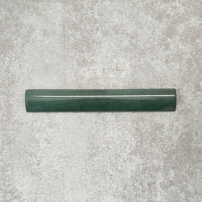 Zellige Royal Green Bullnose 3 × 20cm Moroccan-style ceramic trim tile in rich deep green tones, displayed with a smooth rounded edge and glossy glaze, arranged on a textured grey background to highlight the handcrafted zellige-effect finish and decorative edging profile.