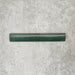 Zellige Royal Green Bullnose 3 × 20cm Moroccan-style ceramic trim tile in rich deep green tones, displayed with a smooth rounded edge and glossy glaze, arranged on a textured grey background to highlight the handcrafted zellige-effect finish and decorative edging profile.