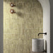 Bathroom featuring Zellige Weald Green 6.5×20cm Moroccan-style ceramic brick tiles installed on the walls within an arched shower area, showcasing soft green tonal variation, a handmade-look finish, and styled with minimalist concrete basin and matte black tapware.