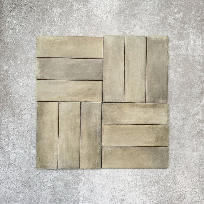 Flat lay of Zellige Weald Green 6.5×20cm Moroccan-style ceramic brick tiles, shown in a basketweave layout, highlighting soft green and earthy tonal variation, irregular edges and a handmade-look glazed finish on a neutral background.