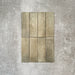 Flat lay of Zellige Weald Green 6.5×20cm Moroccan-style ceramic brick tiles, highlighting soft green and earthy tonal variation, irregular edges and a handmade-look glazed finish on a neutral background.