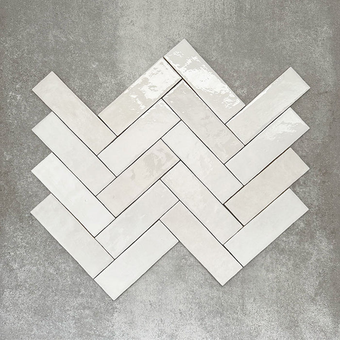 Zellige White brick tiles arranged in a herringbone pattern, featuring a glossy white finish with natural tonal variation.