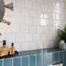 Zellige White Square 13.2cm x 13.2cm Moroccan style tiles, showcasing a softly irregular surface and glossy white finish that catches the light, paired with rich blue tiles and decorative accessories.