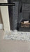 Fireplace hearth featuring Fayrouz Picasso Honed Finish Natural Marble 5cm x 20cm tiles, showcasing striking grey veining on a white marble background, paired with a traditional cast iron fireplace and neutral carpet.