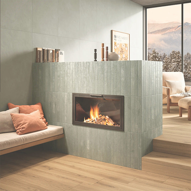 Jumairah Green 5x40 vertical wall tiles installed around a modern fireplace, creating a soft green feature wall with a Mediterranean feel